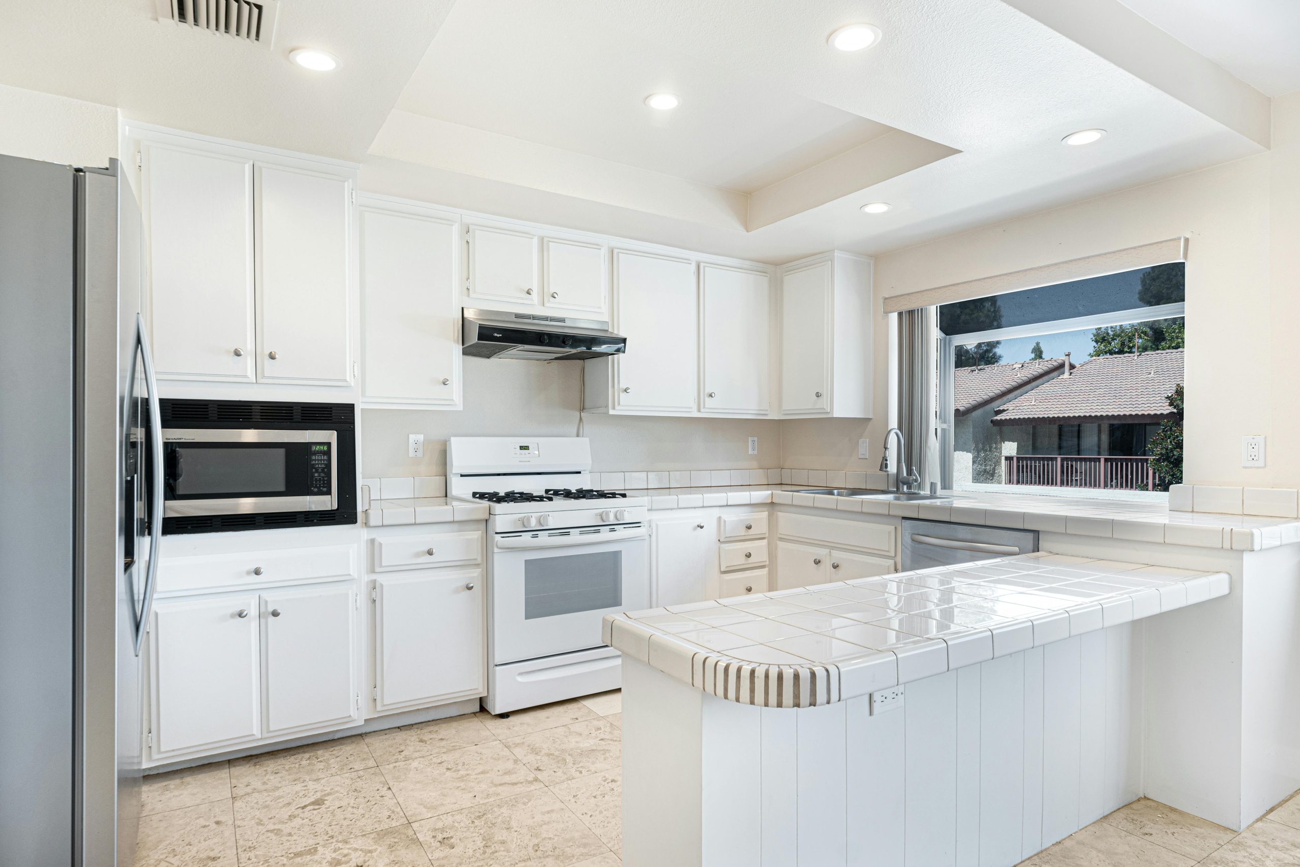 Bright and spacious modern kitchen with white cabinets and stainless steel appliances.