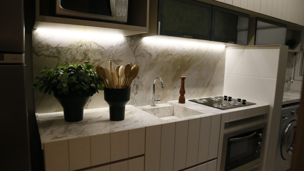 Stylish modern kitchen featuring a marble countertop, plants, and appliances.